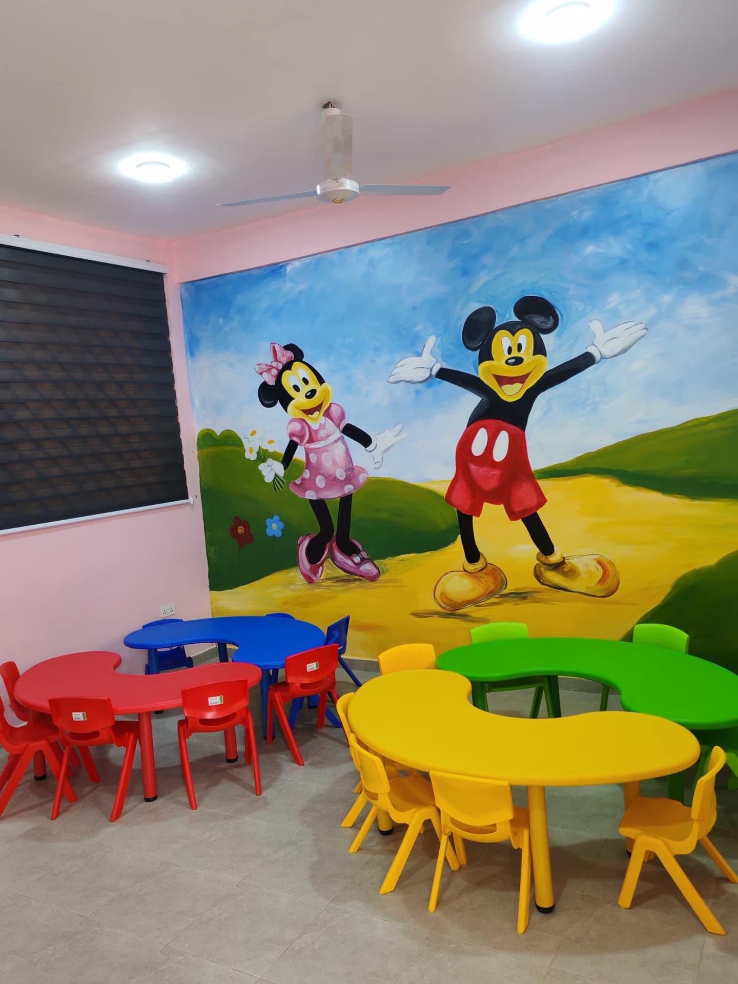Creche playroom with a Mickey and Minnie Mouse wall mural and colourful children's tables and chairs