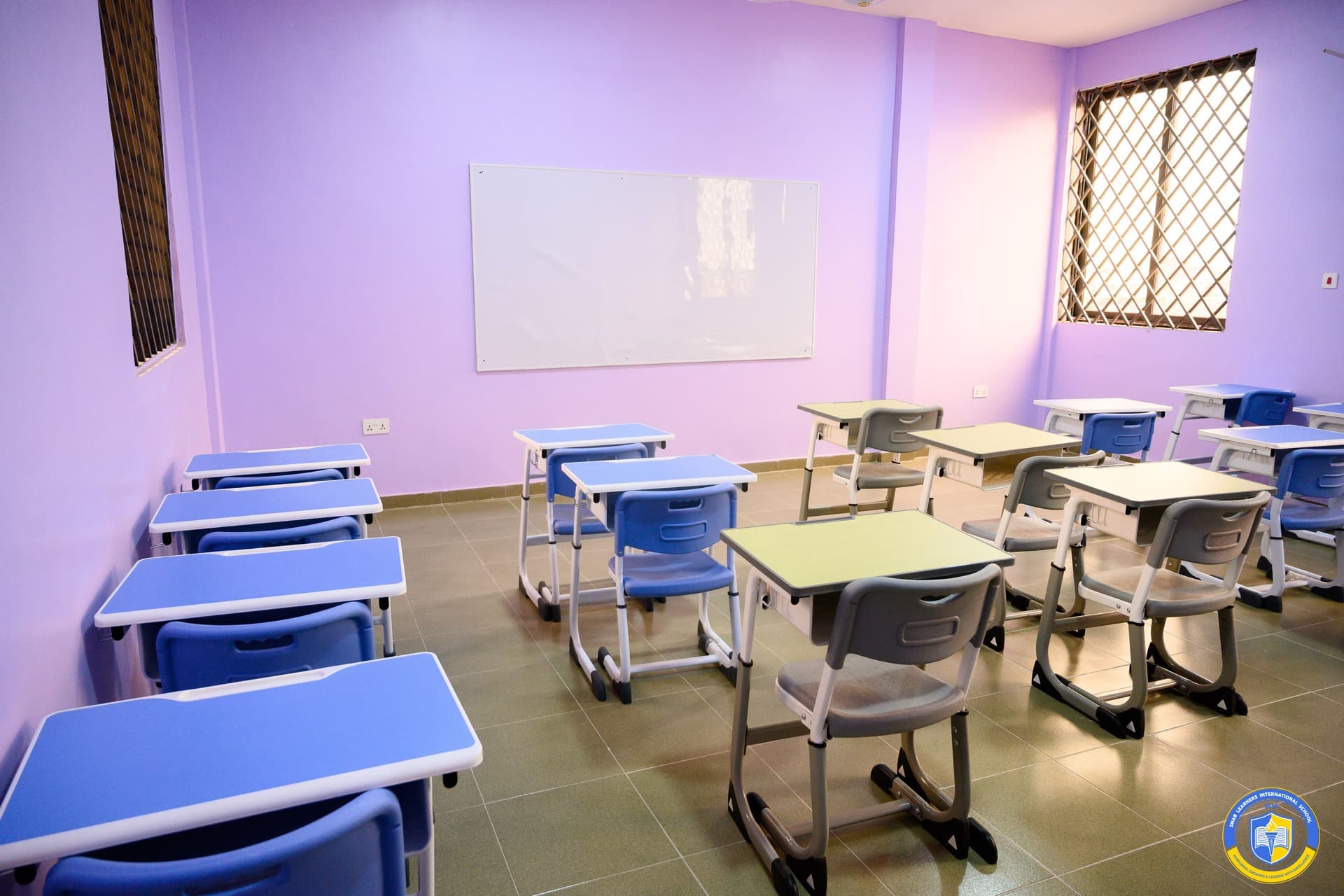 Junior High School classroom with a whiteboard and rows of blue desks with grey chairs